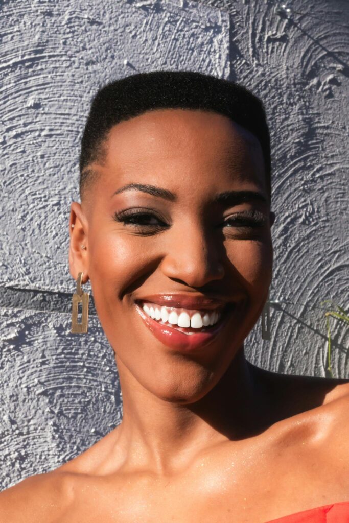 Bright and joyful portrait of a woman with a radiant smile, captured in natural sunlight.